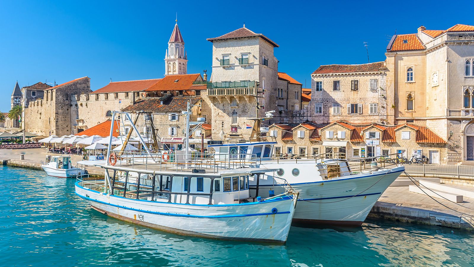 Historic Mediterranean harbor with stone buildings, terracotta roofs and docked boats