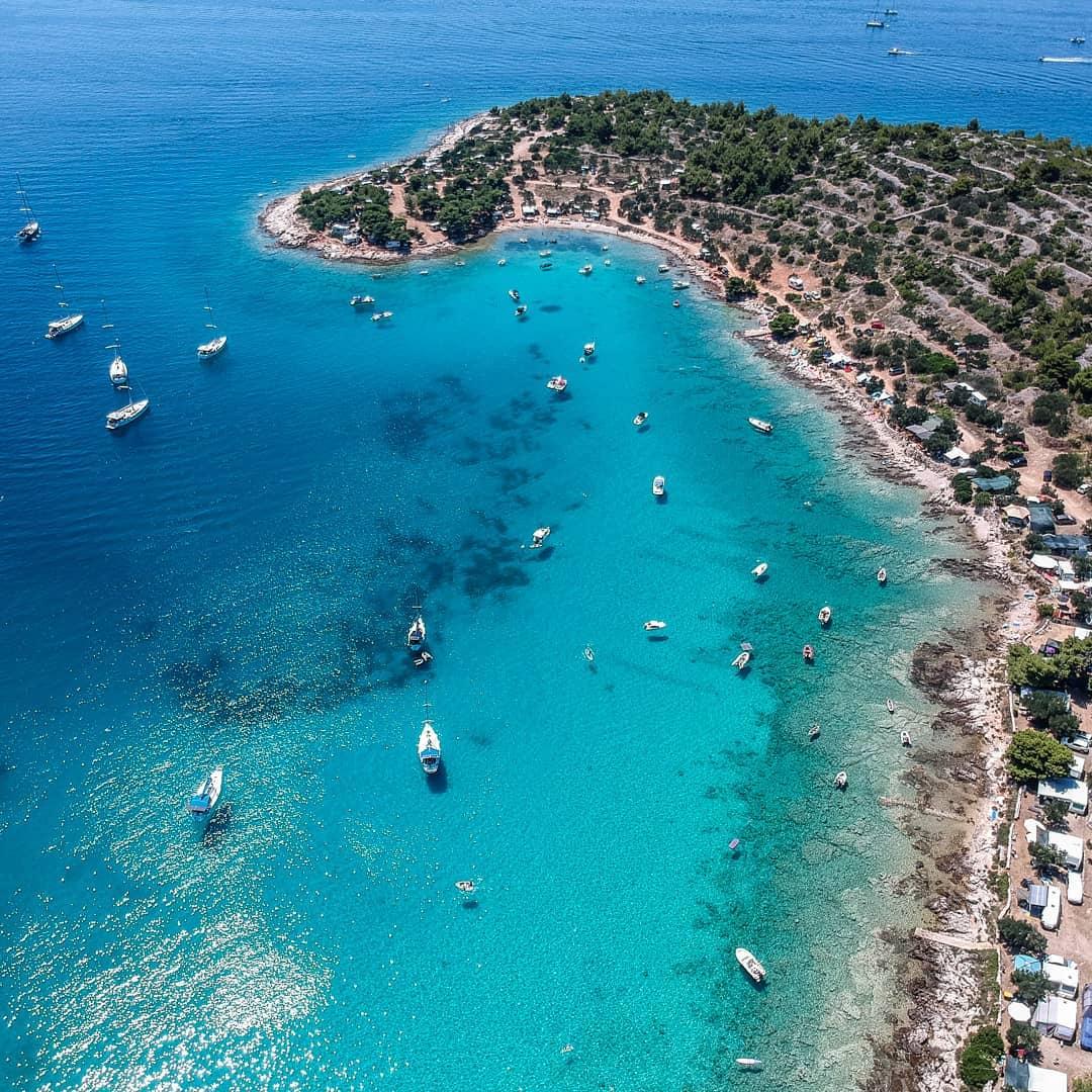 Aerial view of an Adriatic coastal bay with turquoise water and anchored boats
