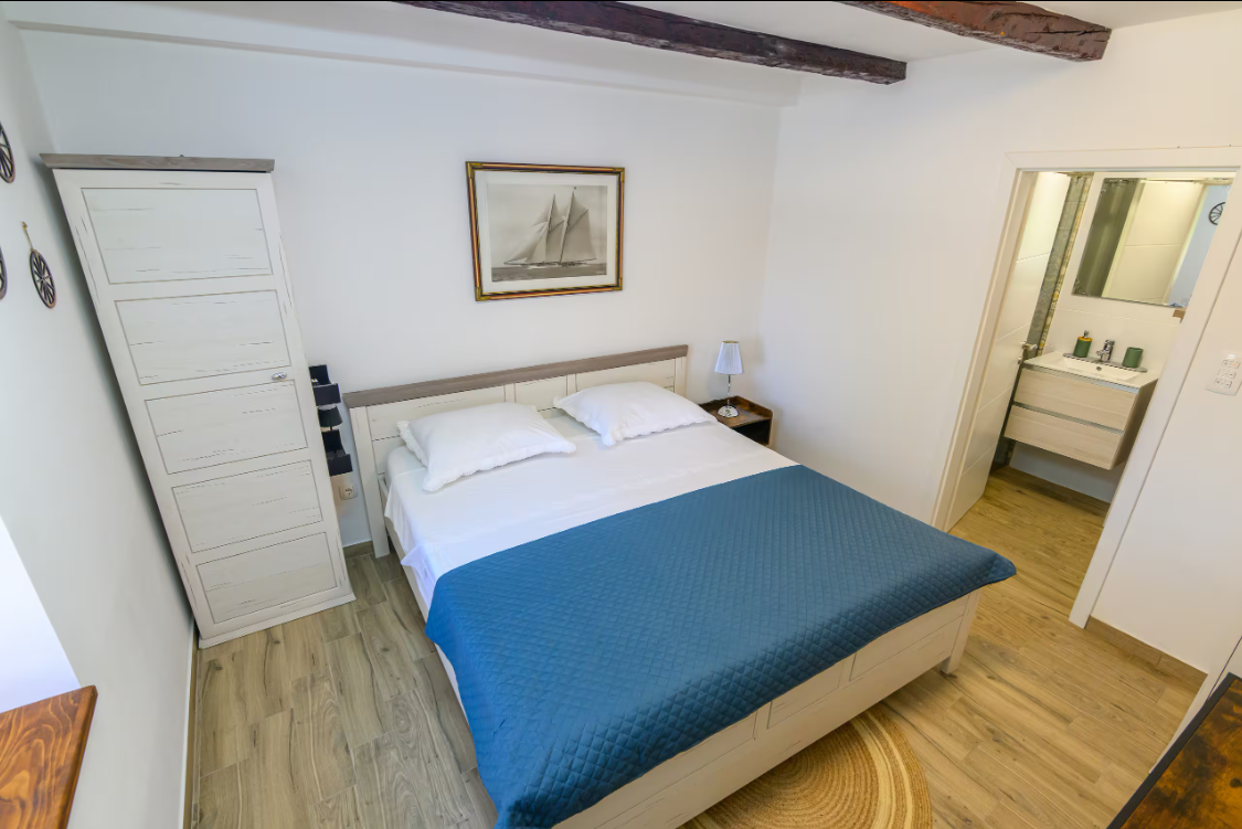 Bedroom with queen bed, stone wall and wooden beams